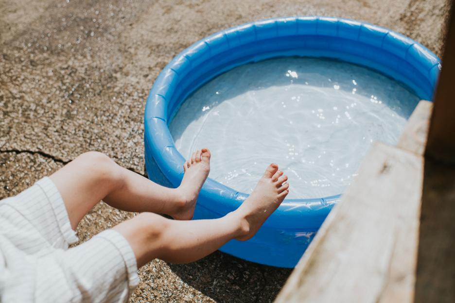 Child's feet dangling over a blue inflatable pool.