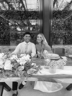 Black and white photo of a bride and groom sitting at their wedding reception.