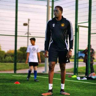 A soccer coach stands on a field.
