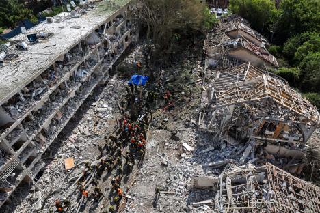 Aerial view of rescue workers at the site of a building destroyed by a missile strike.