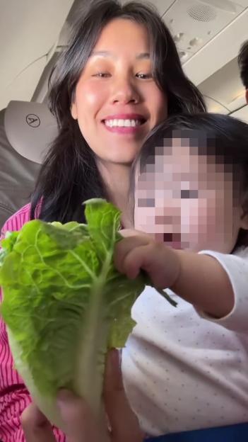 Woman on airplane holding lettuce leaf for baby.