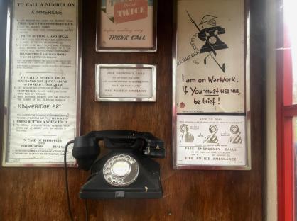 Interior of a wartime telephone box with instructions and posters.