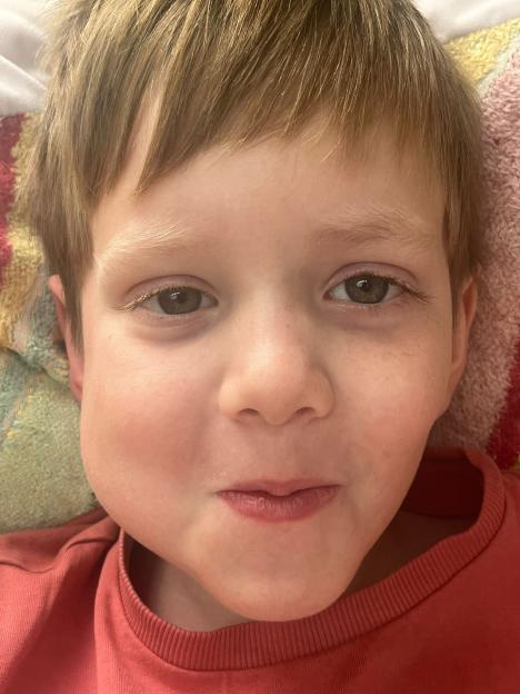 Smiling boy in hospital giving thumbs up.