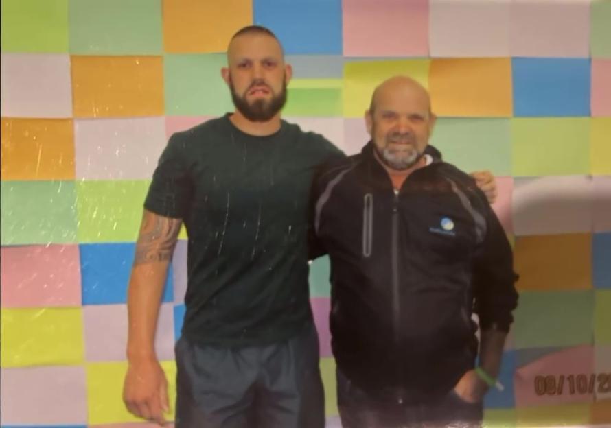 Two men posing together in front of a colorful background.