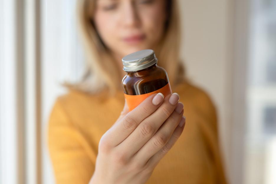 Woman examining a supplement bottle.