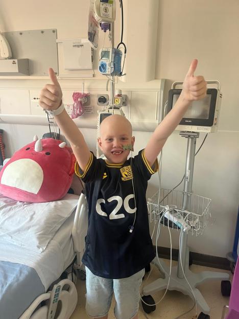 Seven-year-old boy in hospital giving thumbs up.