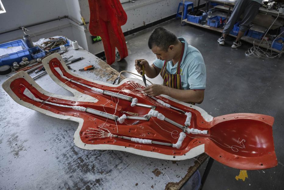 A worker assembles the internal framework of a sex doll mold in a factory.