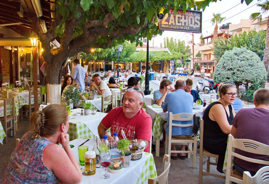 People dining outdoors at a Greek taverna.