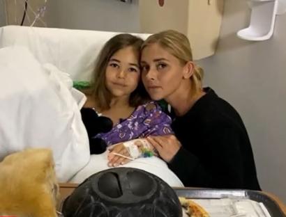 A 9-year-old girl recovering in a hospital bed with her mother.