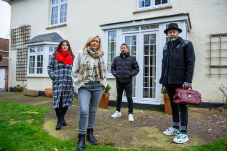 Four people standing outside a house.