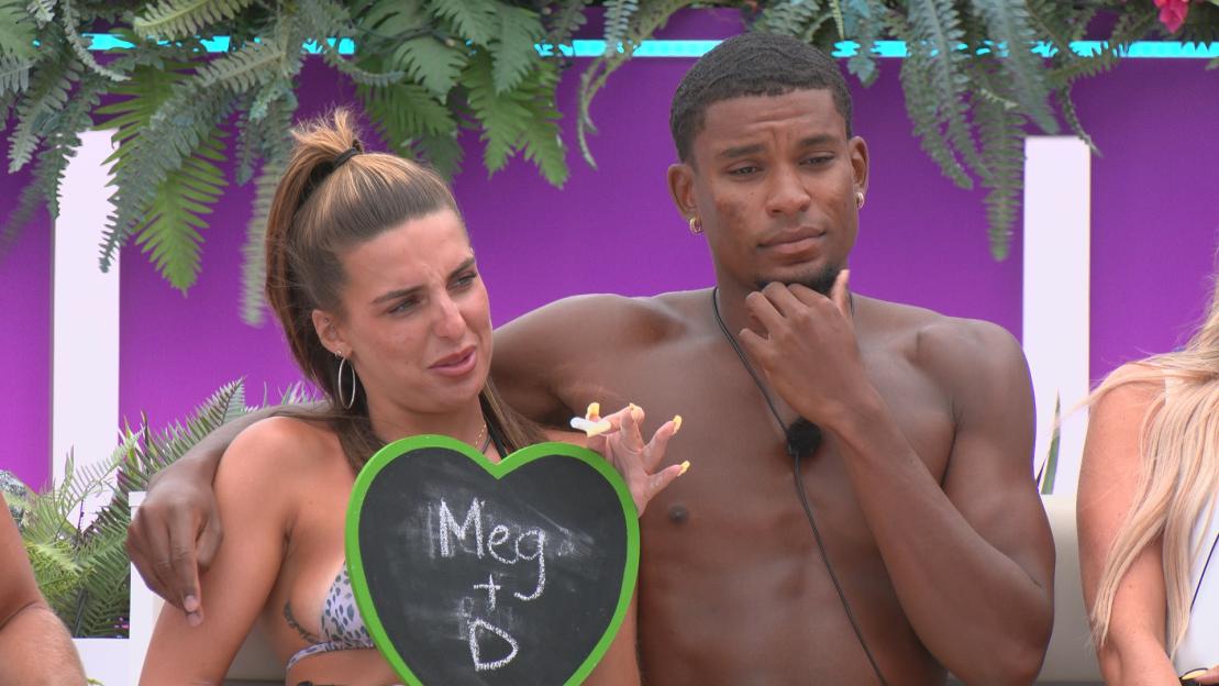 Meg and a man holding a heart-shaped sign that says