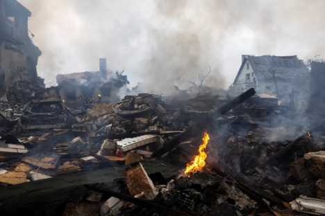 Smoldering rubble and flames in the aftermath of a fire.