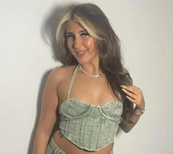 Woman in sage green corset top and necklace.