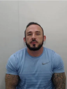 Mugshot of a man in a light blue shirt.
