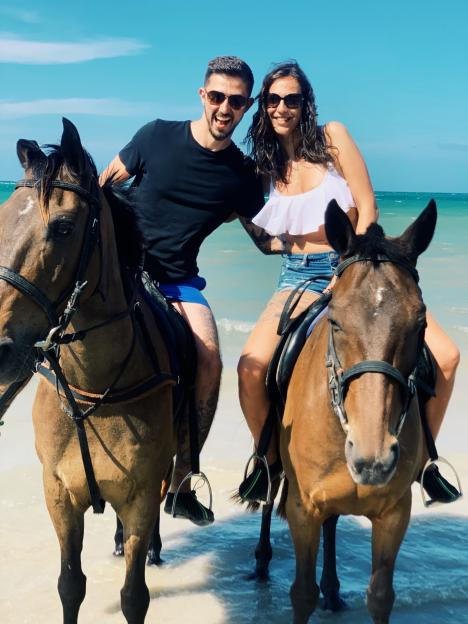 Couple horseback riding on a beach.