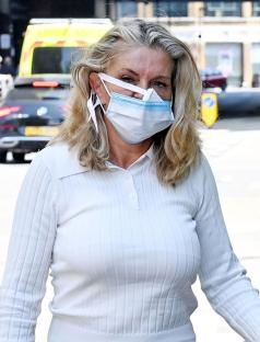 Danniella Westbrook leaving a hospital wearing a white top and face mask.