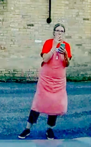 Woman in pink apron using phone.