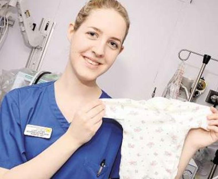 Nurse holding a baby's garment. Possibly Lucy Letby.