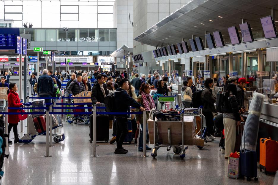 Busy airport check-in counter with passengers and luggage.
