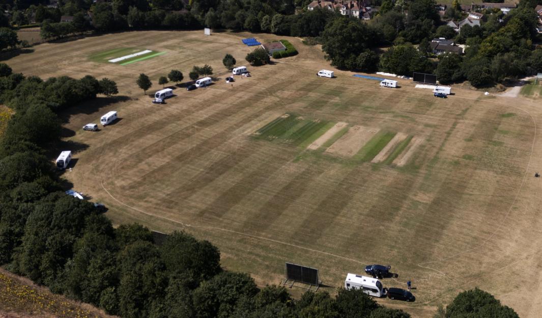 Aerial view of a cricket pitch occupied by caravans.
