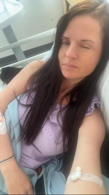 Woman in hospital bed with IV.