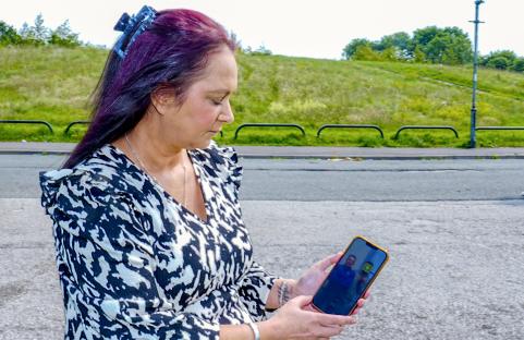 A woman looks at a phone displaying a photo of the teenager who killed her daughter.