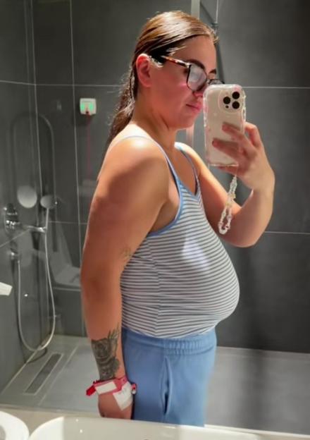 Woman in a bathroom, taking a selfie before breast reduction surgery.