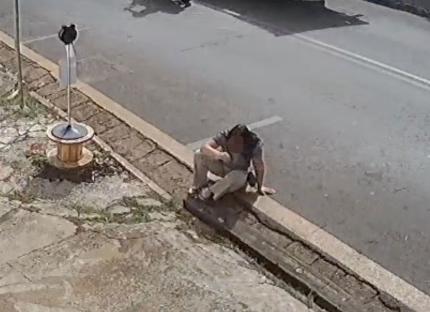 CCTV grab of a woman sitting on the curb after falling out of a moving Uber.