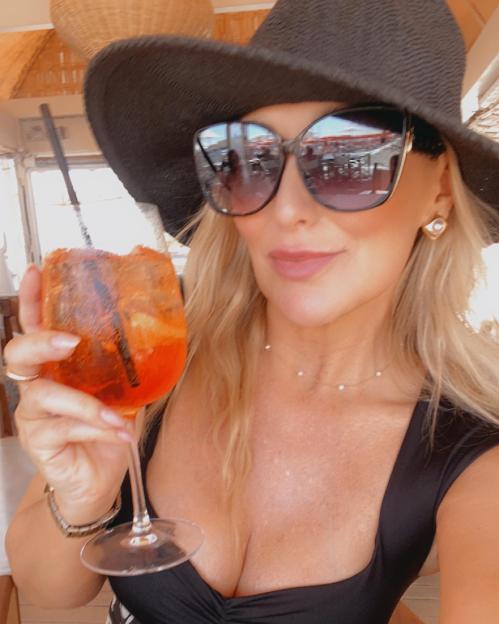 Woman in a sunhat holding an Aperol Spritz.