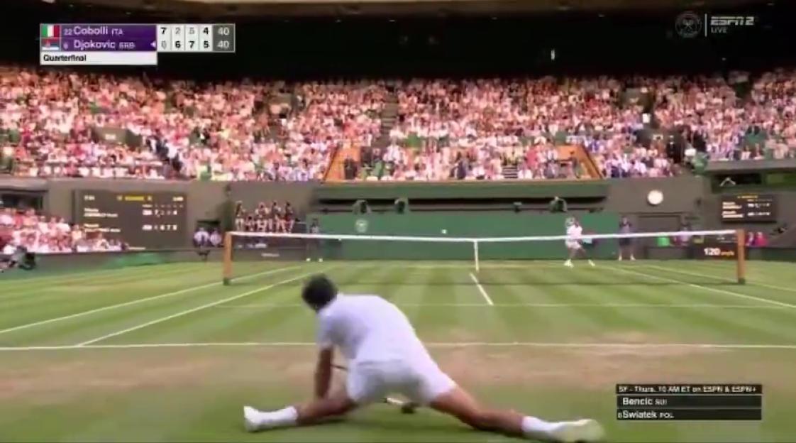 Tennis player in a split during a match.