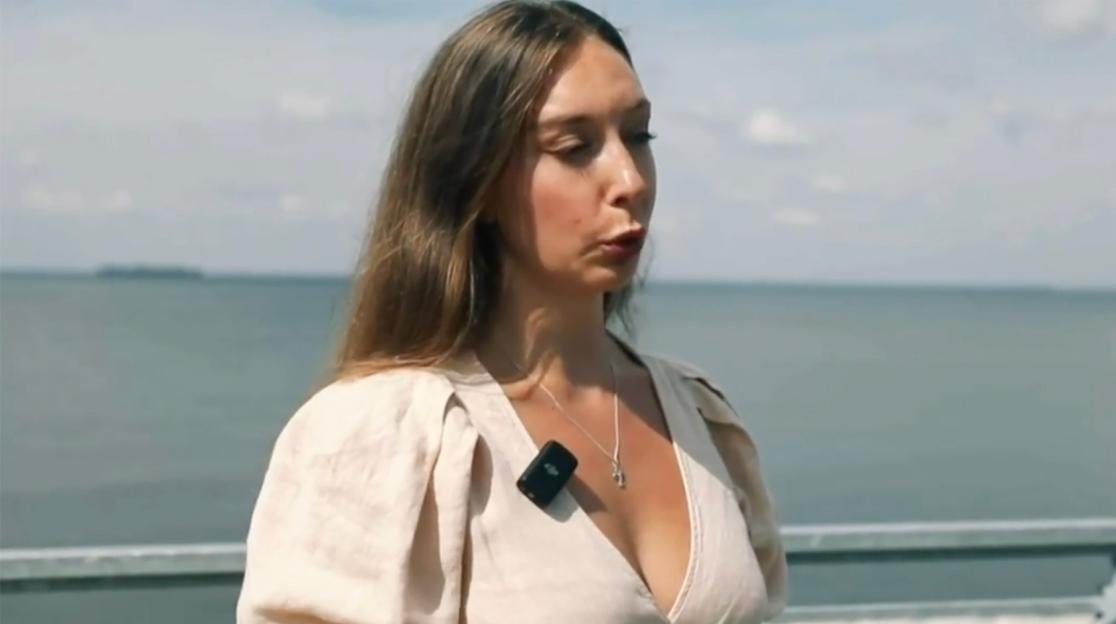 Woman speaking in front of a body of water.