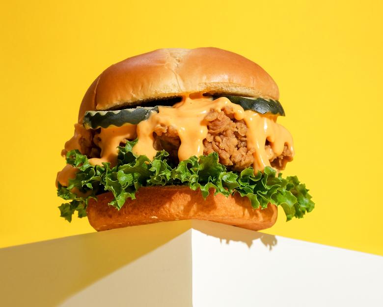 Fried chicken sandwich with lettuce and sauce.