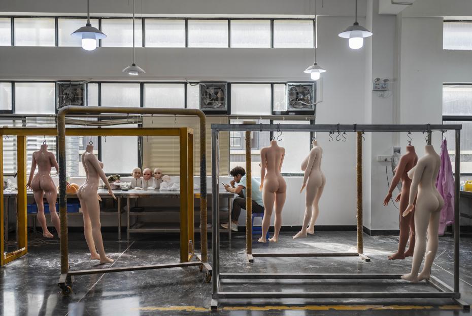 Factory worker taking a break amongst drying silicone sex dolls.