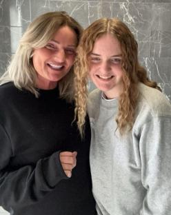 Photo of a woman and a girl smiling together in a bathroom.