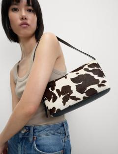 Woman carrying cow-print handbag.