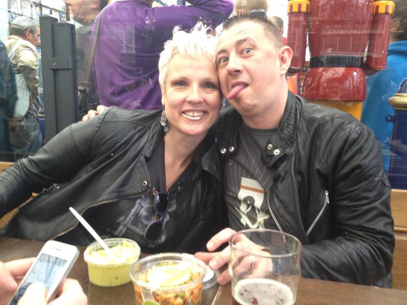 Photo of two people sitting at a table, one with their tongue sticking out.