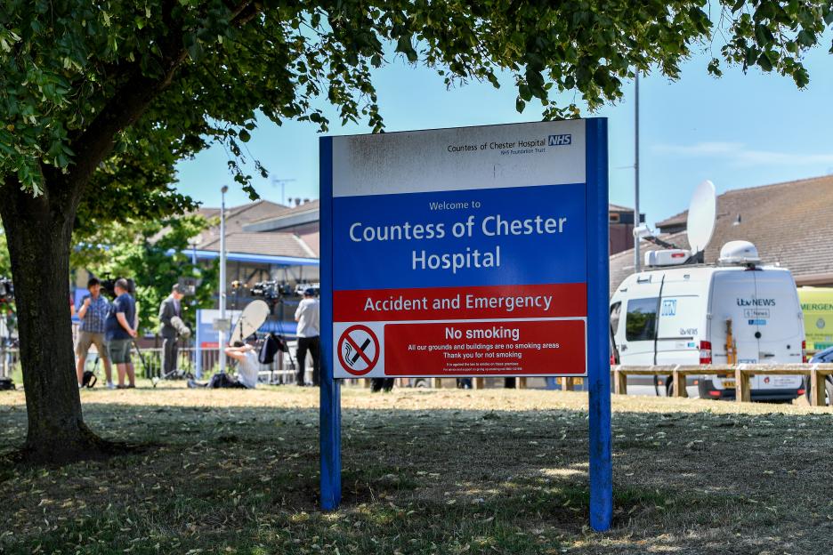 Photograph of a Countess of Chester Hospital sign with media vans in the background.