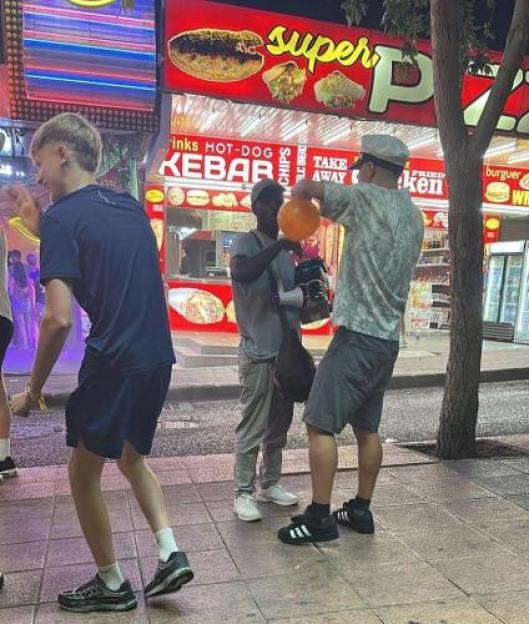 Three people on a street at night, one holds an orange balloon.