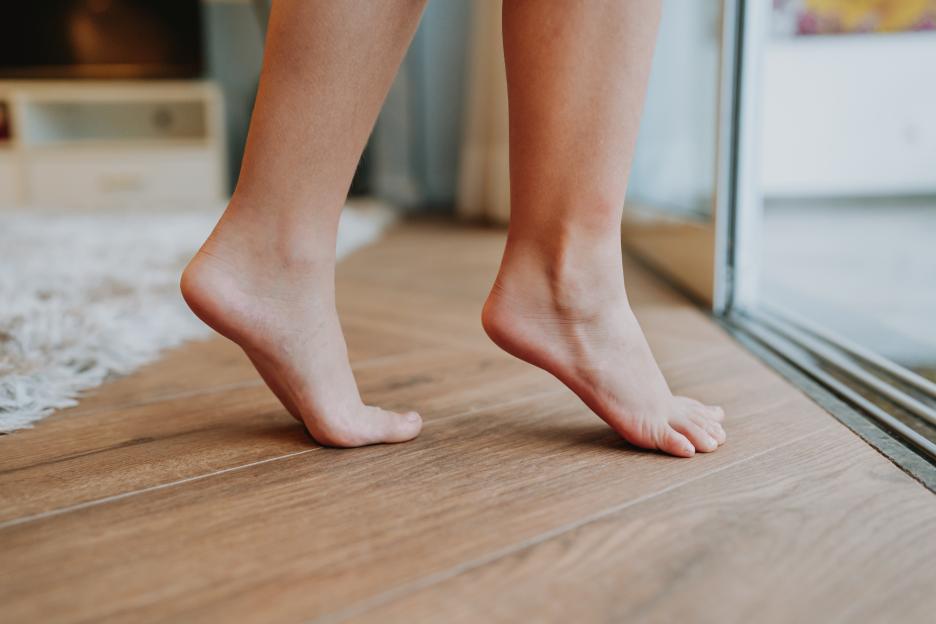 Bare feet walking on tiptoe across a wood floor.