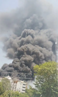 Large plume of black smoke rising above buildings.