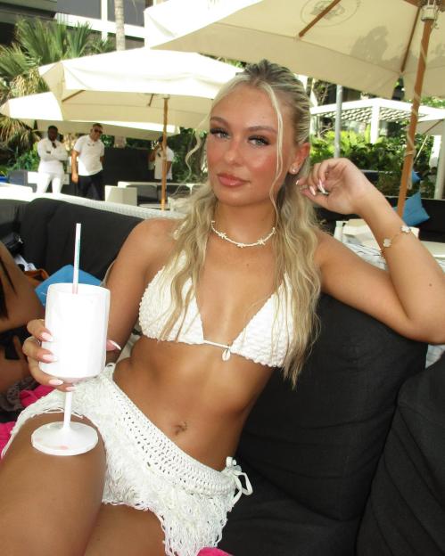 Woman in white bikini holding a drink.