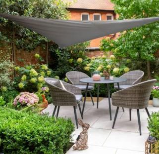 Grey patio furniture set under a grey shade sail in a garden.