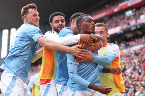 a group of soccer players huddle around a player wearing a jersey that says ' manchester city ' on it