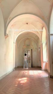 Person exploring an abandoned Italian palace hallway.