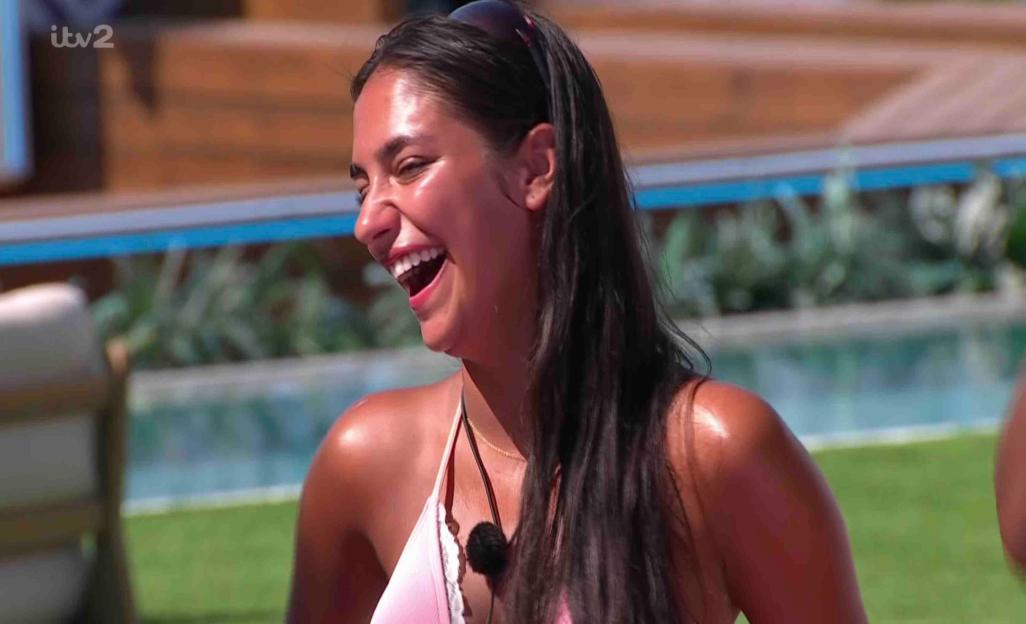 A woman laughing by a pool.