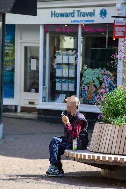 Person smoking on a bench in Trowbridge.