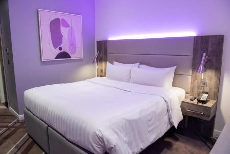 Hotel room with a large bed and purple lighting.
