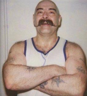 Charles Bronson, a prisoner known for taking an art teacher hostage, with arms crossed.