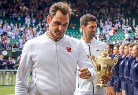 Roger Federer and Novak Djokovic holding trophies after a Wimbledon tennis match.