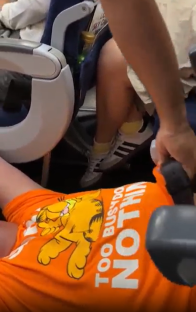Person in orange Garfield shirt reclined in airplane seat.